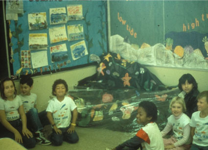 Seven students in a classroom which is decorated with artwork from Ocean Immersions